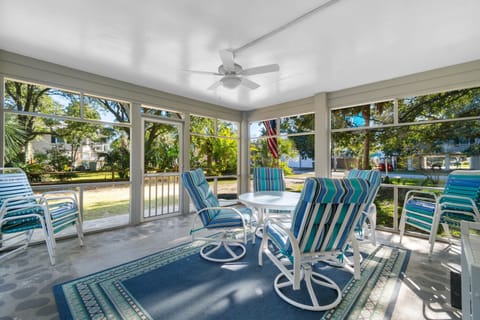 Relax in your screened porch with colorful striped chairs and garden views—perfect for morning coffee or evening conversations.