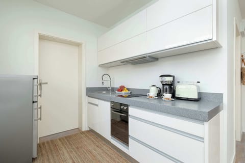 A white modern kitchenette with a small coffee maker and sleek design.