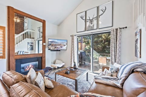 Relax in this inviting living space featuring plush leather seating, a stone fireplace, and charming mountain décor. Sliding doors lead to a private balcony—perfect for taking in the alpine air or watching the snowfall.