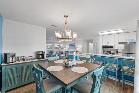 Gather around the coastal-inspired dining table where turquoise chairs create the perfect spot for your morning coffee and vacation planning.