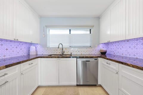 Fully equipped kitchen featuring stone countertops, stylish beadboard cabinetry, and stainless steel appliances, including a dishwasher. Perfect for preparing any meal!