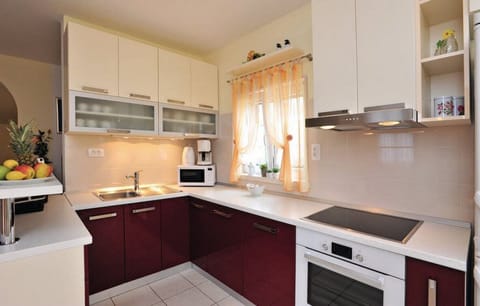 Fully equipped kitchen in one of the apartments features rich red lower cabinets and a functional layout for preparing meals.