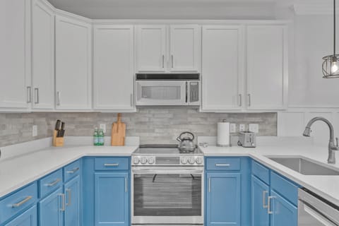 Modern kitchen featuring sleek blue cabinetry, new stainless steel appliances, and quartz countertops.