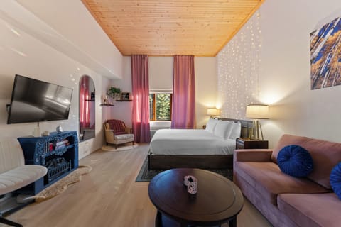 Relax in your stylish studio with warm wood ceiling, plush sofa, and modern amenities creating the perfect mountain retreat atmosphere.