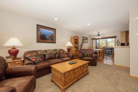 Sink into plush leather sofas in your spacious living room, where warm wood tones and mountain artwork create the perfect retreat after adventure-filled days.