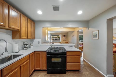 MAIN HOUSE: Fully equipped kitchen with warm wood cabinetry, tiled backsplash, and modern appliances for all your cooking needs