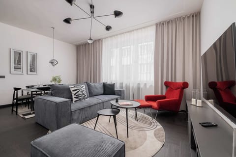 A bright living room with a gray sectional sofa, a round coffee table, and a large window letting in natural light.