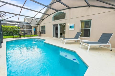 Step outside to your private oasis featuring a sparkling pool framed by a spacious deck. Lounge on stylish chaise chairs while enjoying the natural light filtering through the screened enclosure, creating a relaxed atmosphere.