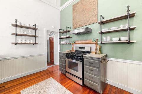 Compact kitchen featuring industrial-style floating shelves and a gas range.