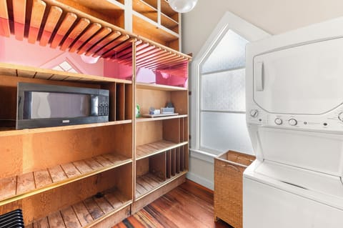 Convenient full-sized washer and dryer next to extensive storage shelving.