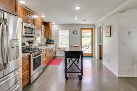 Modern kitchen | Stainless steel appliances, wood cabinetry, center island, and patio access