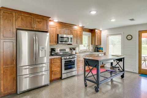 Modern kitchen | Stainless steel appliances, wood cabinetry, center island, and patio access