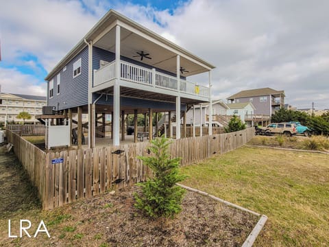 Elevated coastal home with covered balcony and parking below, nestled in a peaceful beachside neighborhood.