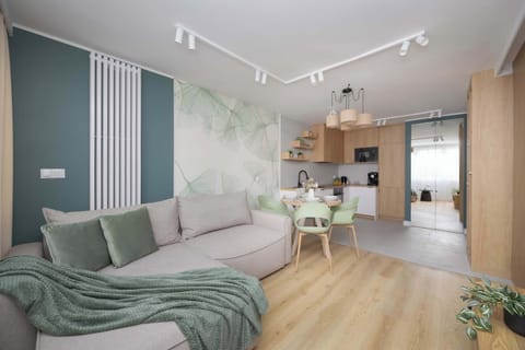 A bright living room with a gray sofa and soft lighting, featuring modern wooden accents. The space feels inviting and well-lit with large windows.