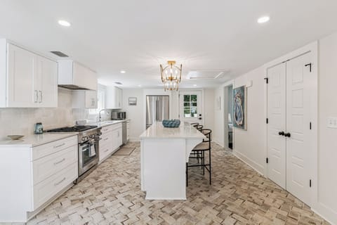 You'll love cooking in this stunning white kitchen with marble counters, stainless appliances, and elegant herringbone floors that invite culinary adventures.