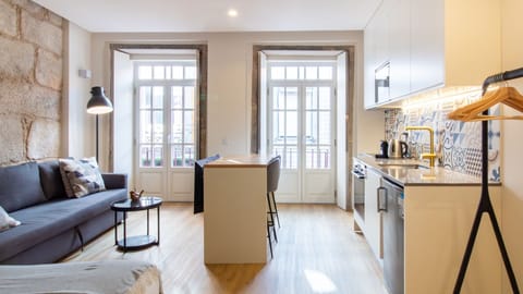 Bright, stylish open-plan living space with French balconies and a fully equipped kitchen – perfect for relaxing or working remotely. #PortoStay #DesignApartment #CityView