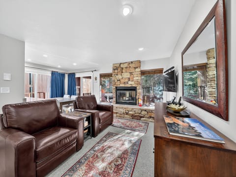 Unwind in your spacious living room where rich leather seating faces a stunning stone fireplace. Watch the flames dance while you relax on comfortable sofas, enjoying mountain views through expansive windows.