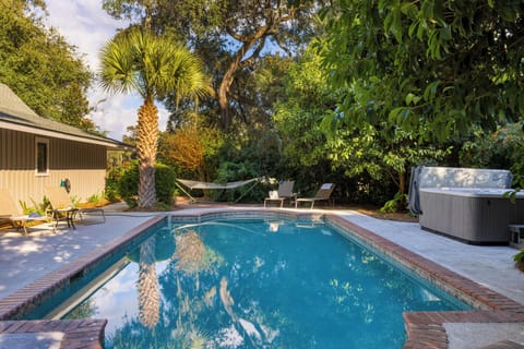 Private backyard oasis with pool, hot tub, and hammock under the palms.