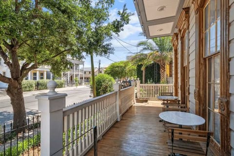 Spacious front porch with seating overlooking a classic New Orleans streetscape.