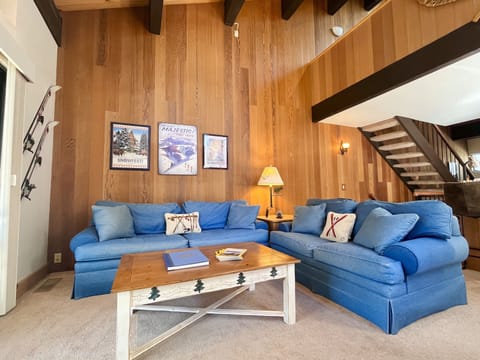 Living room features high ceilings, smart-tv, gas fireplace, and natural light