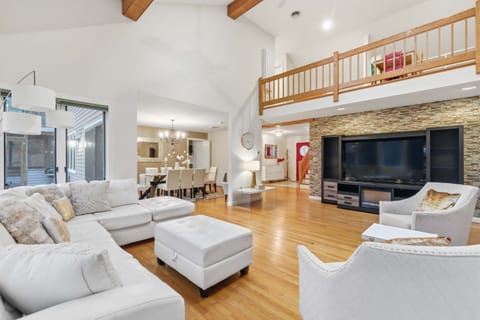 Expansive main living space with soaring ceilings, oversized sectional, and forest views—perfect for group movie nights or relaxing mornings