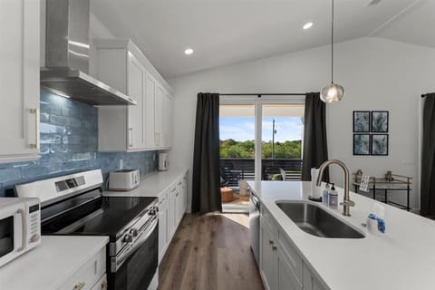 Fully equipped kitchen with stainless steel appliances, quartz countertops, and access to the outdoor balcony.