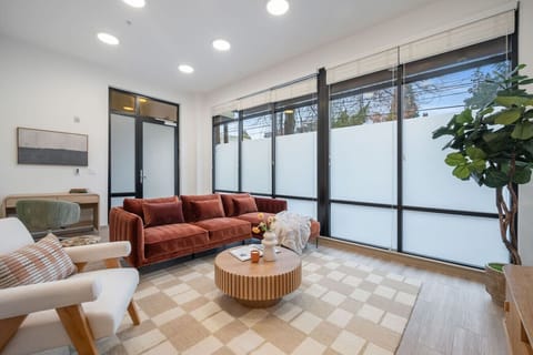 Bright and modern living space featuring floor-to-ceiling windows, cozy seating, and stylish decor — perfect for relaxing after a day out.
