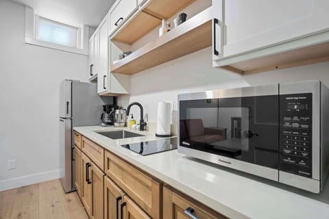 This compact kitchenette is efficiently designed with a stovetop, microwave, and open shelving stocked with essentials. Clean lines and bright finishes make it a comfortable space for quick meals and morning coffee.