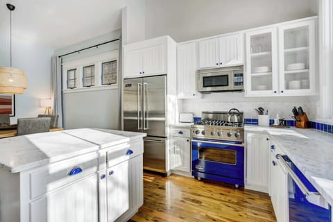 A bright kitchen featuring marble counters, stainless appliances, and bold blue tile details, fully equipped for easy meal prep.