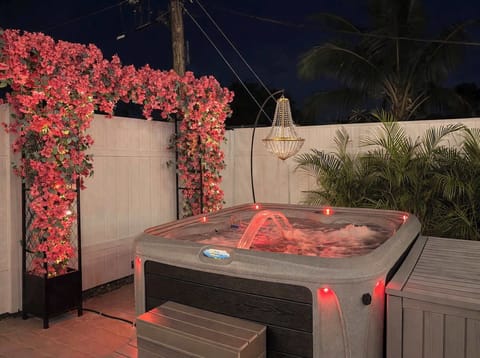 Unwind in the private hot tub under the stars, surrounded by lush greenery and soft lighting for a relaxing evening!