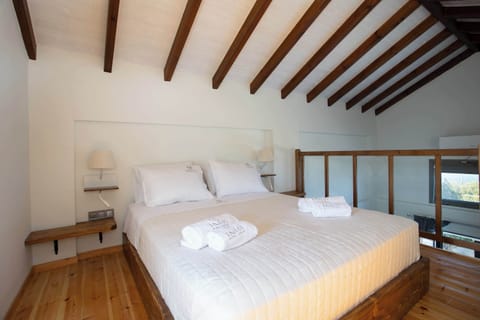 Bedroom with High Wooden Beams and Sunlit Interior
Spacious bedroom featuring a comfortable bed, warm architectural details, and gentle natural light streaming through the windows.