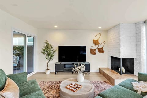 Light-filled living room featuring floor-to-ceiling windows, a cozy fireplace, and a large Smart TV. An expansive, open layout makes this the ideal spot for both quiet relaxation and lively family gatherings.