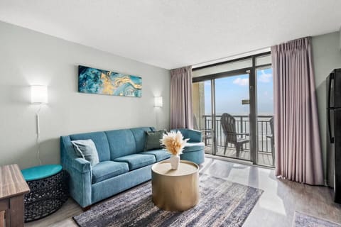 Beach-themed living room filled with bright natural light and a full-size sofa with queen sofa sleeper. Enjoy a cozy, comfortable space that opens to a private oceanfront balcony, perfect for relaxing during short or long beach getaways.