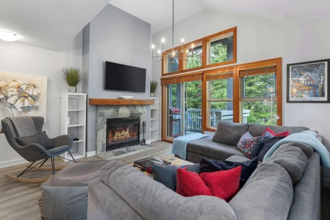 - Bright living room with forest views and cozy seating  
- Warm fireplace setting perfect for relaxing after outdoor fun  
- Large windows bring in fresh Whistler light  

