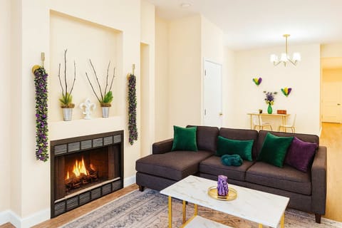 Living room with fireplace, plush sofa, and gold-and-marble coffee table in Mardi Gras-inspired purple, green, and gold.