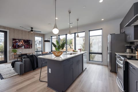 Unit 1: Fully equipped kitchen with stainless steel appliances, basic cooking essentials, toaster, coffee machine, and kitchen island seating.