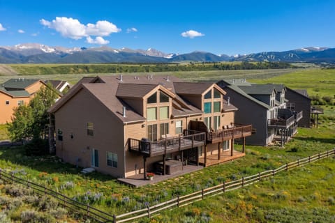 Mountain retreat nestled in a peaceful valley with expansive decks overlooking majestic peaks and rolling meadows, offering a serene Colorado escape.