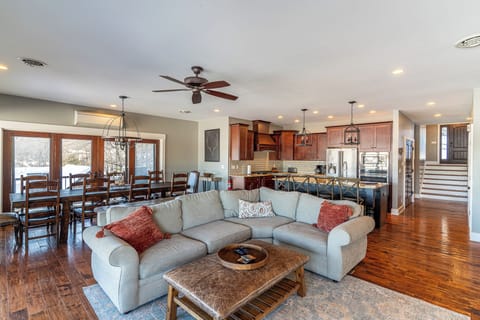 Open living with stone fireplace, chef’s kitchen, wrap-around deck, lake views