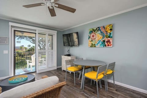 Bright coastal dining with teal walls, vibrant art, and sunny yellow seating.