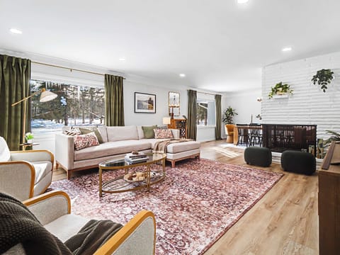 Bright living room w/ cozy seating, large windows & warm accents for relaxed gatherings