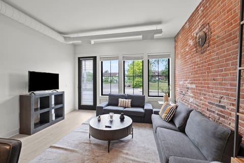 ✨ Our living room features a plush couch perfect for lounging, a large TV for movie nights, and a stunning brick wall that adds character to the space.