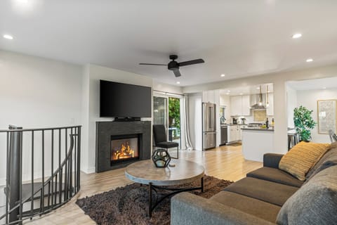Cozy living room with fireplace, TV, ceiling fan, and sofa.