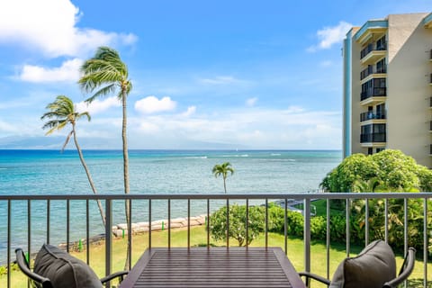 Balcony perch with table for two, ocean views stretching beyond palms and blue skies.