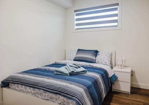 The bedroom is with a queen bed, side with table lamp
