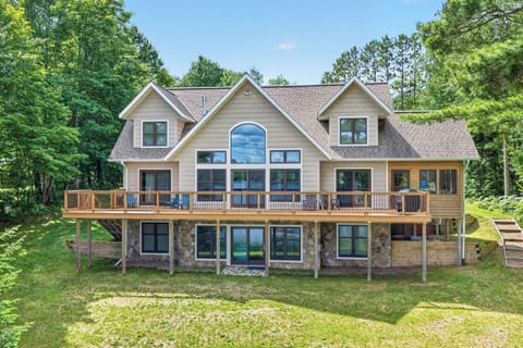 A large beige cabin with many windows and a large deck and walk out basement