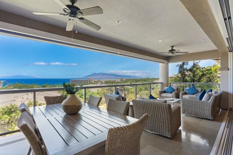 Relax on a covered lanai featuring comfortable seating and a dining table, overlooking the sparkling Pacific Ocean