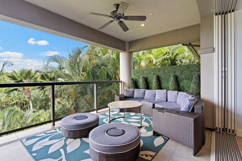 A shaded outdoor lounge featuring a sectional sofa and ottomans, perfect for relaxing with tropical views