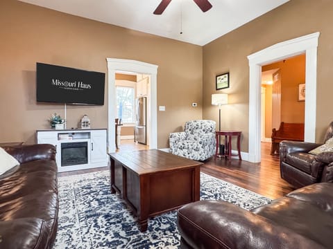 Warm and inviting Great Room with comfy leather couch, loveseat and recliner and Flat Screen Smart TV just off the kitchen for a perfect setup for families/groups to relax and reconnect at Aussie Cottage.