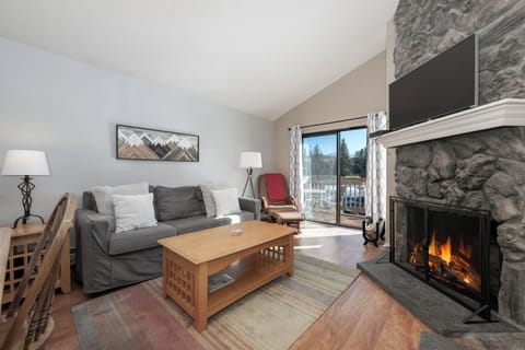 Unwind in your cozy living room where crackling flames dance in the stone fireplace, creating the perfect mountain retreat atmosphere.