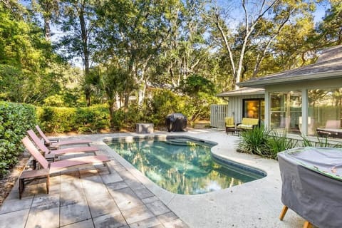 Private pool area surrounded by lush greenery and comfortable lounge chairs.